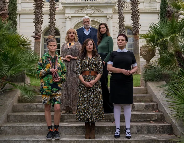 Characters stand on stairs in front of a grand building in "La Source du mal".