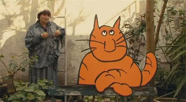 Woman stands by cartoon cat in "Les plages d'Agnès".