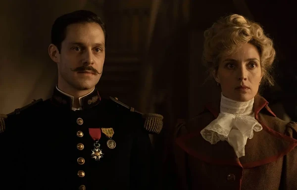 A man in uniform and a woman stand side by side in "Paris Police 1900 Season 1".